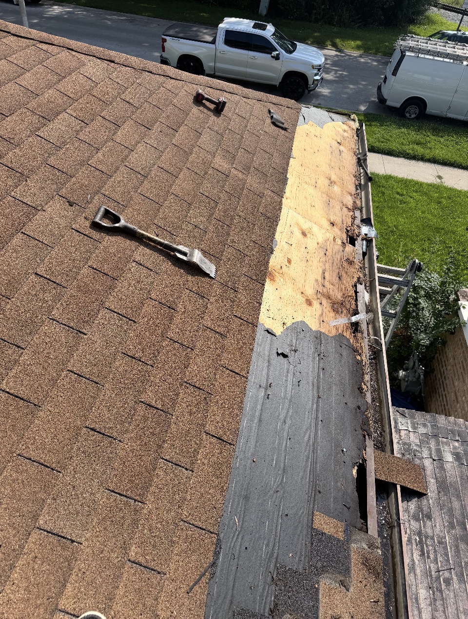 Tear-off in progress exposing fresh plywood at the roof edge